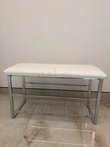 Small metal entryway bench with white cushion and storage rack