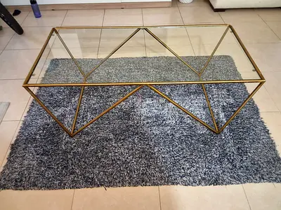 Coffee table of Home Centre brand with glass tabletop and Blue carpet