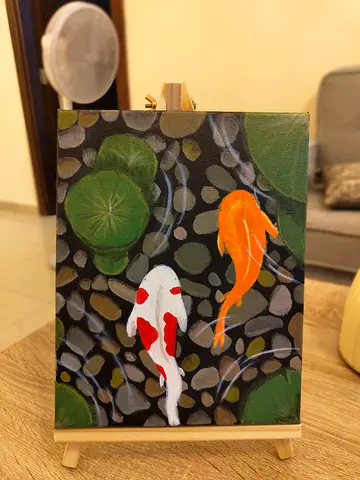 Canvas painting of koi fish on easel.