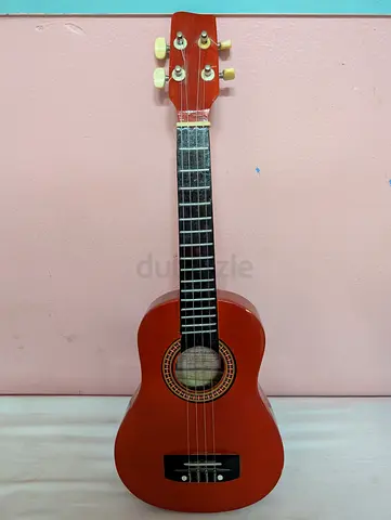 Red wooden four-string ukulele, often categorized as a beginner or childrens instrument