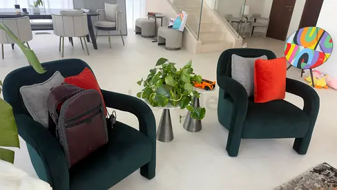 Pair of dark green velvet lounge chairs with cushions and marble side table
