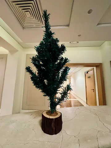 Small artificial tabletop Christmas tree on wooden log base