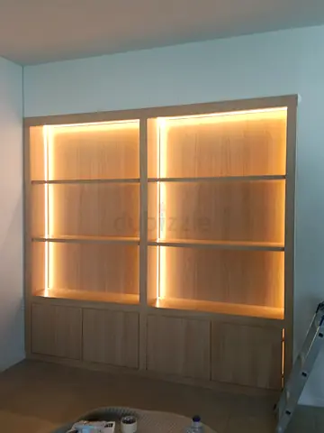 Custom built-in oak display shelves with LED lighting and storage cabinets