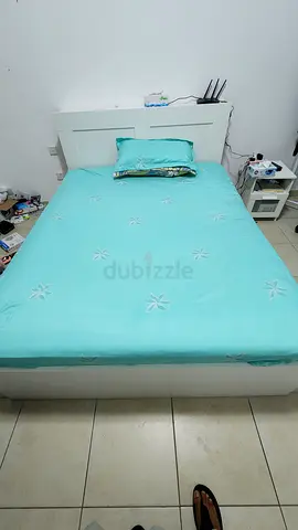 Single white wooden bed frame with mattress and turquoise bedding