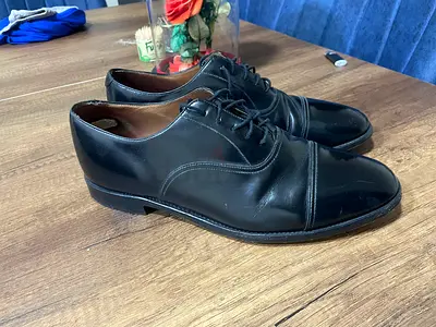 Charles Tyrwhitt black leather cap-toe Oxford shoes with a high-shine finish.