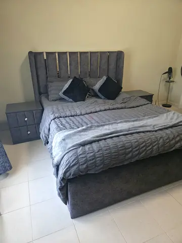 Grey upholstered queen bed with storage and matching bedside tables