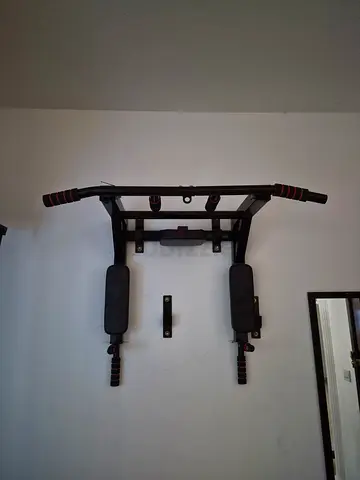 Wall-mounted pull up and dip station with padded armrests and handles