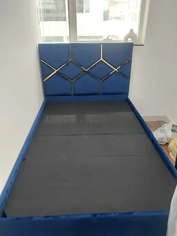 Blue upholstered double bed with decorative headboard
