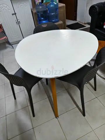 Round white dining table with 4 plastic chairs — used