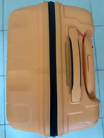 American Tourister Ellipso Spinner luggage in a vibrant apricot blush orange color.