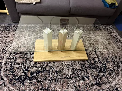 Glass top coffee table with wooden base and decorative pillars