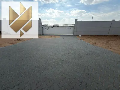 A walled plot of land for rent in Al Sajaa, on a main road, with 25kW electricity and interlocking paving.