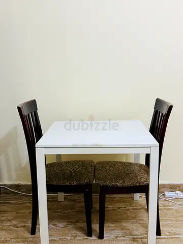 Compact white dining table with two wooden chairs
