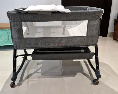 Grey bedside bassinet/crib with storage and wheels, changing pad and extra mattress