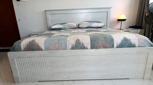 White wooden double bed with headboard and mattress with sofa set