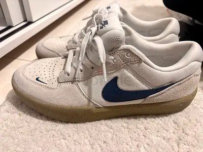 White Nike low-top sneakers with navy swoosh, size not specified