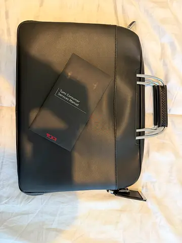 Tumi black leather briefcase with retractable metal handles.