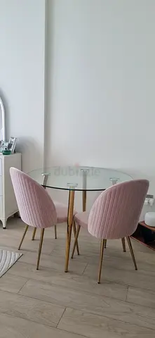Small round glass dining table with two pink upholstered chairs