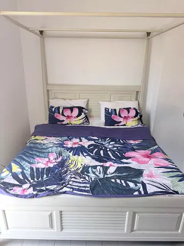 White Four-Poster Wooden Double Bed with Floral Bedding