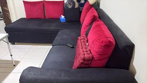 L-shaped black fabric sofa with red cushions - good condition