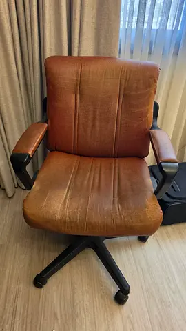 Used brown leather swivel office chair with armrests.