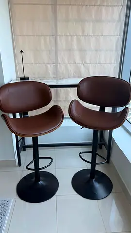 Pair of brown bar stools with swivel seats and footrests
