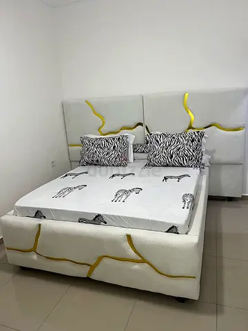 White upholstered queen bed with decorative gold accents