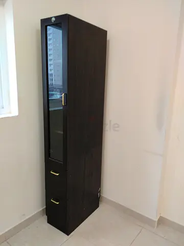 Tall dark wood storage cabinet with glass door and drawers