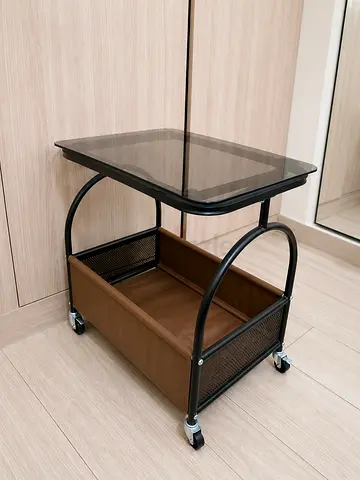 Small wheeled side table with glass top and storage basket