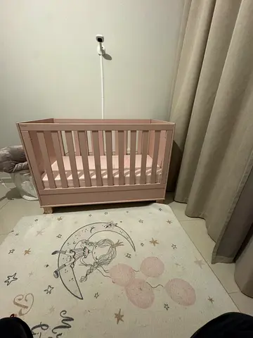 Pink wooden baby crib with mattress and carpet