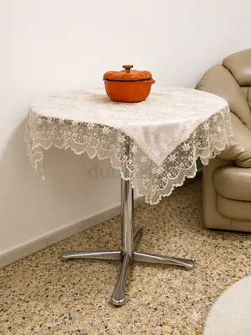 Small round cafe table with metal base and lace tablecloth