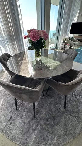 Round glass dining table with 6 grey velvet chairs