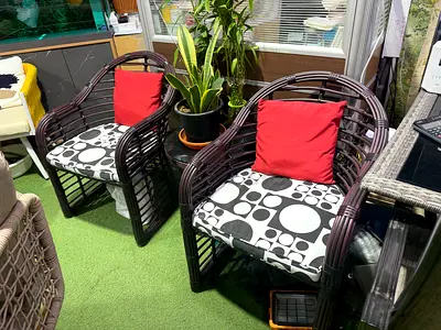 Pair of dark rattan-style armchairs with cushions - good condition