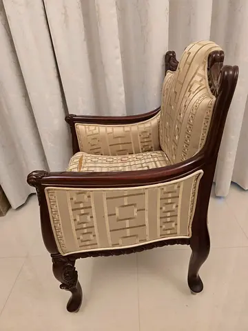 Classic carved wooden armchairs with beige, orange patterned upholstery