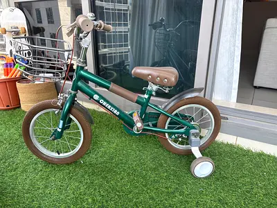 Green kids bicycle with training wheels and basket — good condition