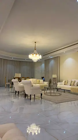 Spacious cream living room set with chandelier and marble flooring