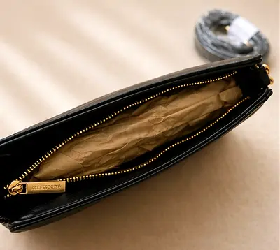 Black leather crossbody bag with gold zipper and detachable strap