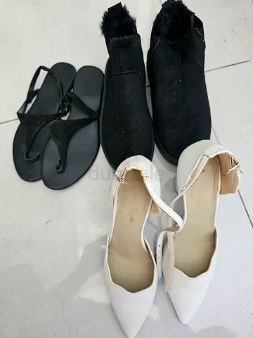 Three pairs of womens shoes – white heels, black sandals, black winter slip-ons