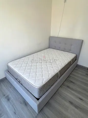 HomeCentre 120x200 Single grey upholstered bed frame with mattress.