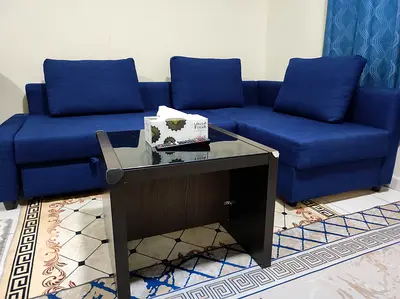 Blue Ikea Sofa Bed - Sofa with Cushions and Glass-top Coffee Table with yellow rug.