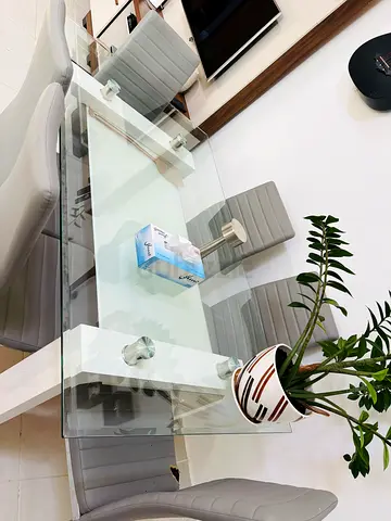 Modern glass dining table with 6 grey upholstered chairs