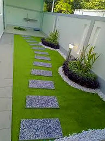Outdoor artificial grass lawn with stepping stones and landscaped planters
