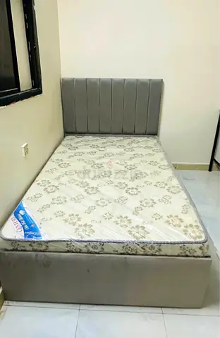 Single bed with grey upholstered headboard and mattress