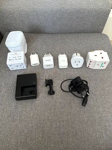 Collection of travel plug adapters, USB chargers and camera battery charger - used
