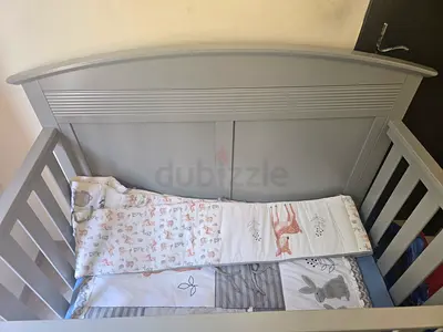 Grey wooden baby crib with fitted mattress and bumpers - good condition