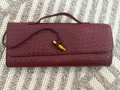 Burgundy woven leather clutch bag with top handle and gold clasp