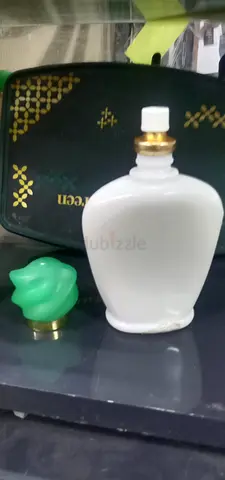 White vintage-style perfume bottle with green cap and small black travel pouch