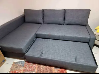 L-shaped grey fabric sofa with pull-out bed — good condition