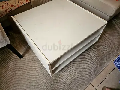 White Ikea coffee table with open shelves on either side and a small drawer — used