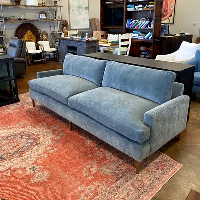 Three-seater blue upholstered sofa with wooden legs